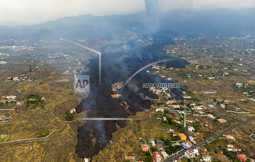 In this Tuesday, Sept. 21, 2021 file photo, lava from a volcano eruption flows destroying houses on the island of La Palma in the Canaries, Spain. A long-dormant volcano on a small Spanish island in the Atlantic Ocean erupted on Sunday Sept. 19, 2021, forcing the evacuation of thousands of people. Huge plumes of black-and-white smoke shot out from a volcanic ridge where scientists had been monitoring the accumulation of molten lava below the surface. (AP Photo/Emilio Morenatti, File)