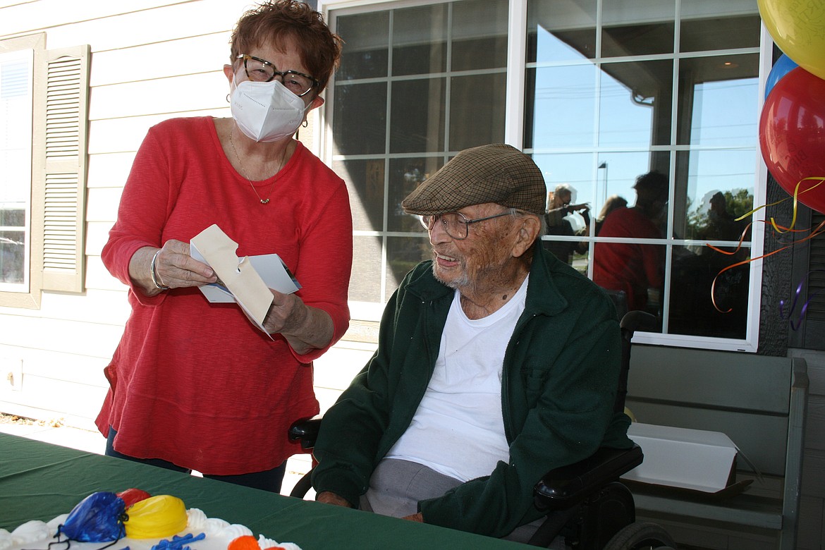 Friend and neighbor Mary Davis reads a birthday card to Dr. Jim Young during his 103rd birthday party.