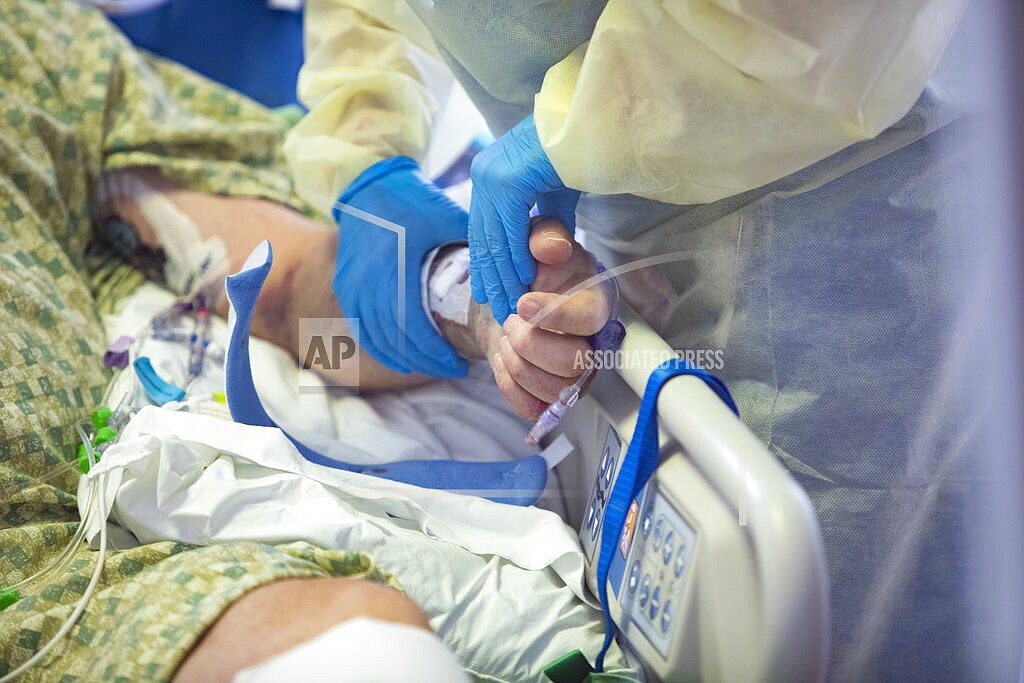 In this Aug. 31, 2021, file photo, a registered nurse holds the hand of a COVID-19 patient in the Medical Intensive care unit (MICU) at St. Luke's Boise Medical Center in Boise, Idaho. An advocacy group for seniors has filed a civil rights complaint against Idaho over the state's "crisis standards of care" guidelines for hospitals overwhelmed during the coronavirus pandemic. Justice in Aging wants the U.S. Department of Health and Human Services to investigate Idaho's health care rationing plan, contending that it discriminates against older adults by using factors like age in prioritizing which patients may get access to life-saving care. (AP Photo/Kyle Green, File)