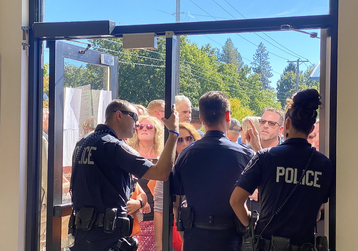 Three Coeur d'Alene Police Department officers stand in the doorway, blocking protesters from entering a Coeur d'Alene School District meeting in September to discuss a temporary mask mandate. (MADISON HARDY/Press)