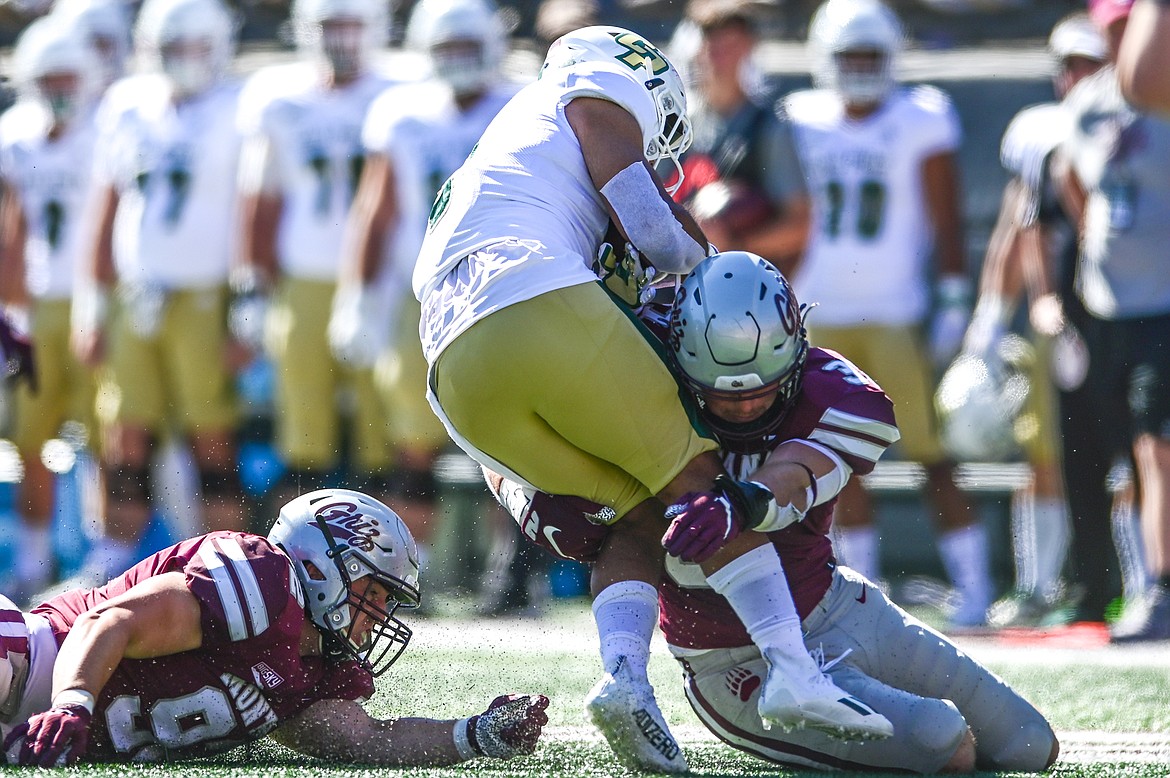 Montana defenders Jacob McGourin (92) and Jace Lewis stop Cal Poly running back Shakobe Parker (8) in the first quarter at Washington-Grizzly Stadium on Saturday, Sept. 25. (Casey Kreider/Daily Inter Lake)
