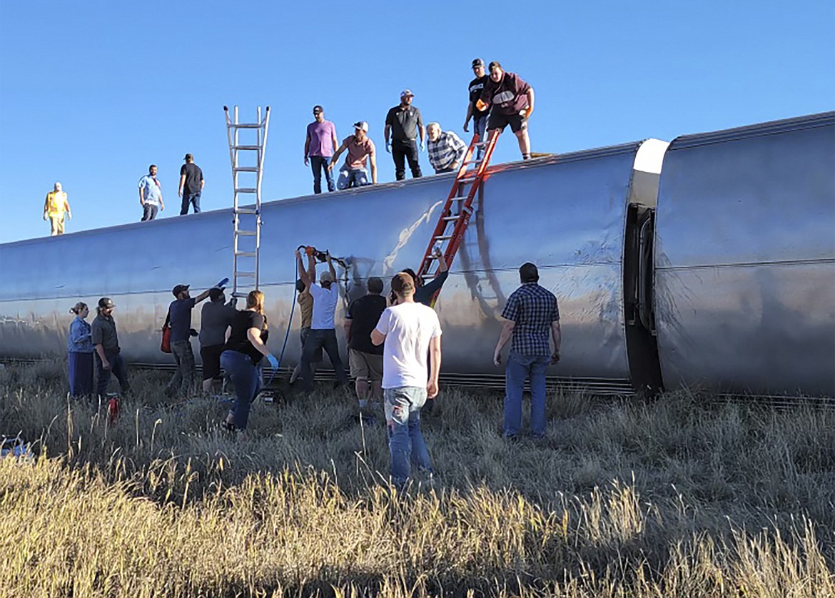 In this photo provided by Kimberly Fossen, people work at the scene of an Amtrak train derailment on Saturday, Sept. 25, 2021, in north-central Montana. Multiple people were injured when the train that runs between Seattle and Chicago derailed Saturday, the train agency said. (Kimberly Fossen via AP)