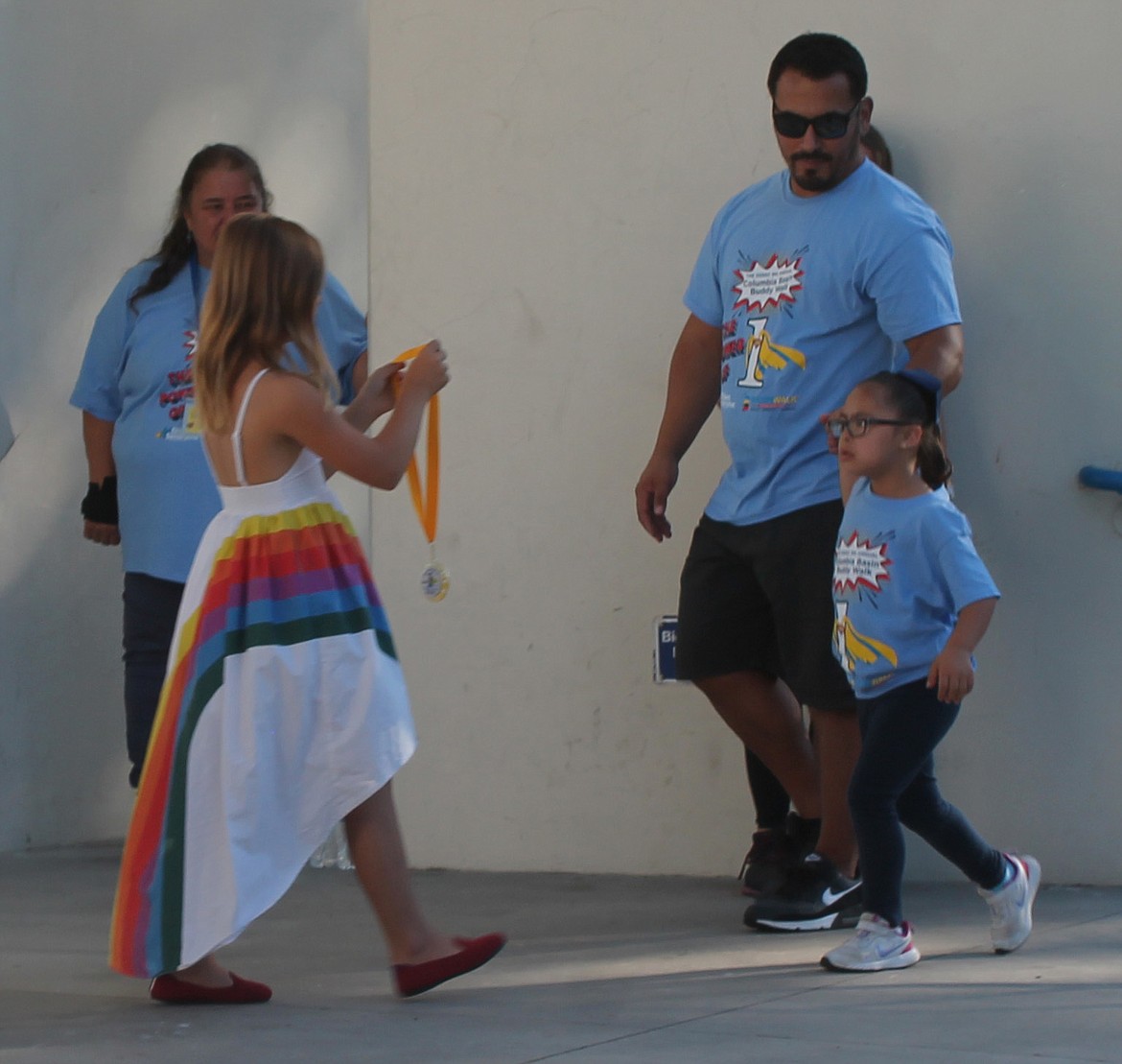 Six-year-old Ava Vasquez, right, prepares to receive her hero medal from Sofia Sanchez before the Down Syndrome Society of Grant County Buddy Walk on Saturday.