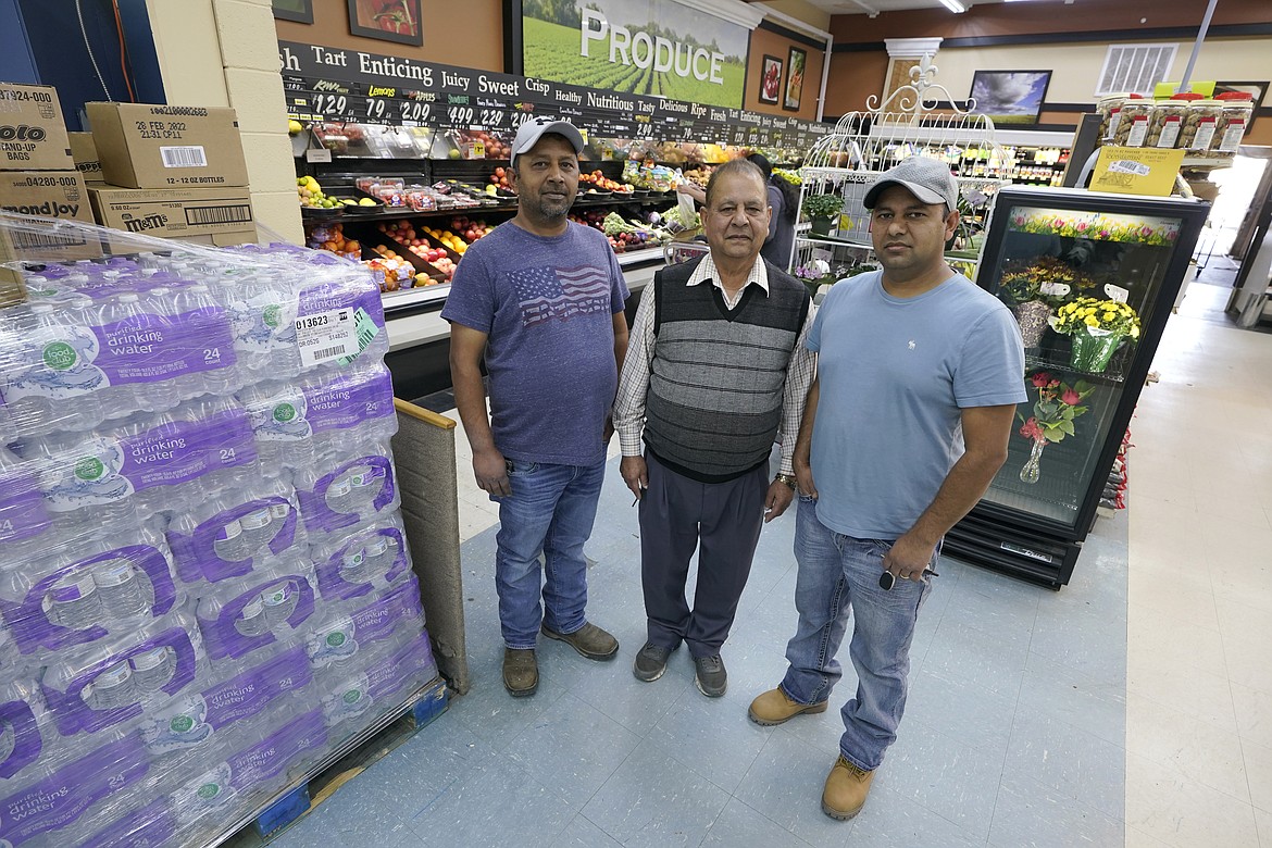 Singh Maan, center, poses for a photo with his sons CJ Maan, left, and Ricky Maan, right, Monday, Sept. 27, 2021, in the grocery store they own in Chester, Mont., near the scene where an Amtrak train derailed Saturday, killing three people and injuring others. When the crash happened, the family rushed to the scene with first-aid and food supplies taken right from the shelves of their store. (AP Photo/Ted S. Warren)