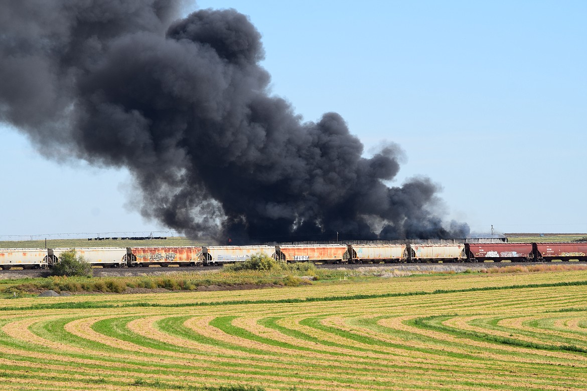 Smoke billows from a fire Wednesday afternoon at an old potato storage building, seen behind a row of railcars, on Road O Northeast in Moses Lake.