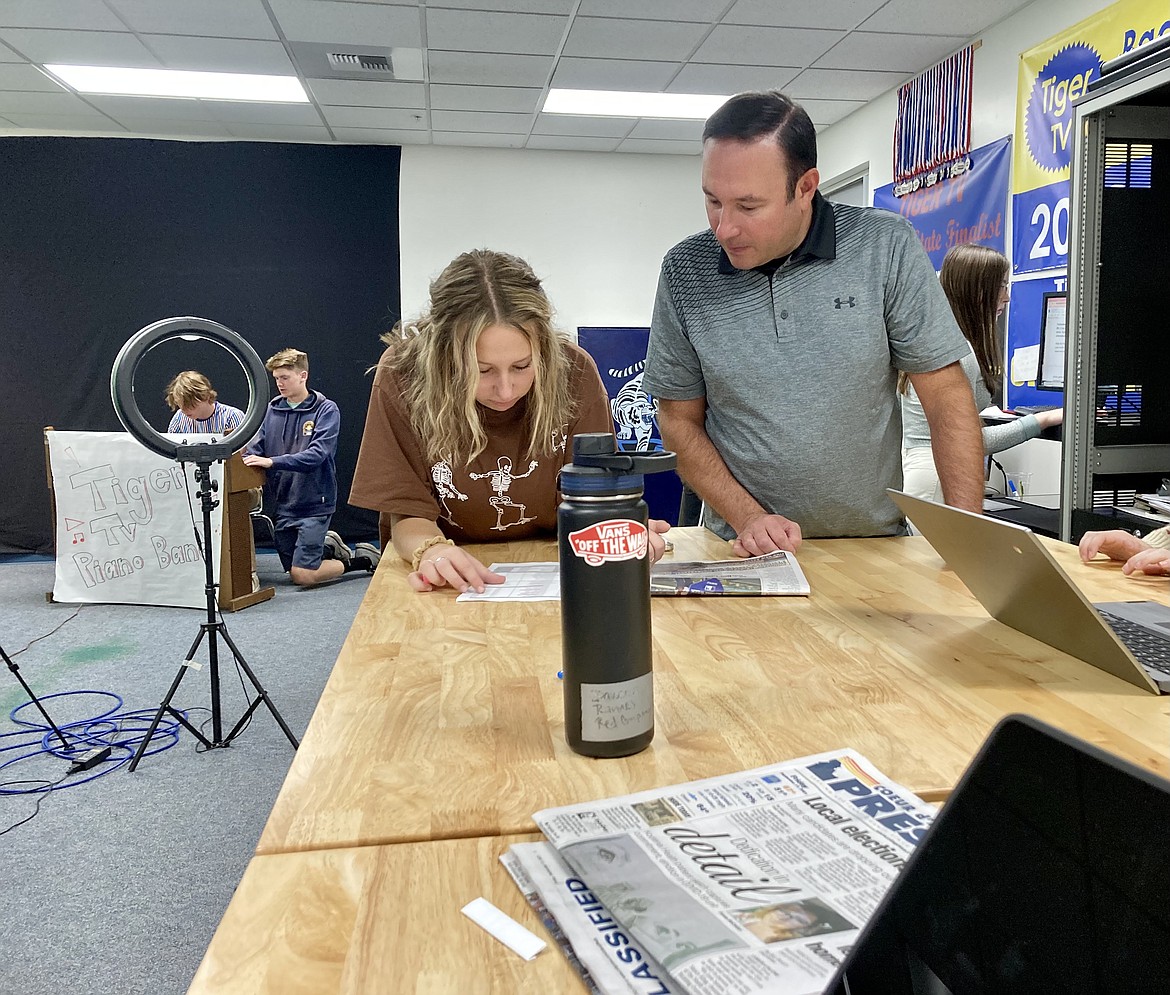 Timberlake High School senior Sami Wilfong gathers sports scores from The Coeur d'Alene Press for the daily broadcast, Tiger TV, while video production teacher Chris Jarstad watches. HANNAH NEFF/Press