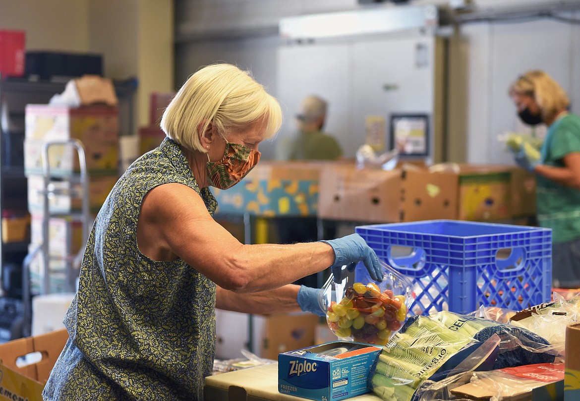 Volunteer Carol Lightbody packs boxes of food prior to a recent food distribution day at the North Valley Food Bank in Whitefish. The North Valley Food Bank and the Farm Hands organizations are hoping to come together to form a Food Resource Center in Whitefish in the future. (Whitney England/Whitefish Pilot)