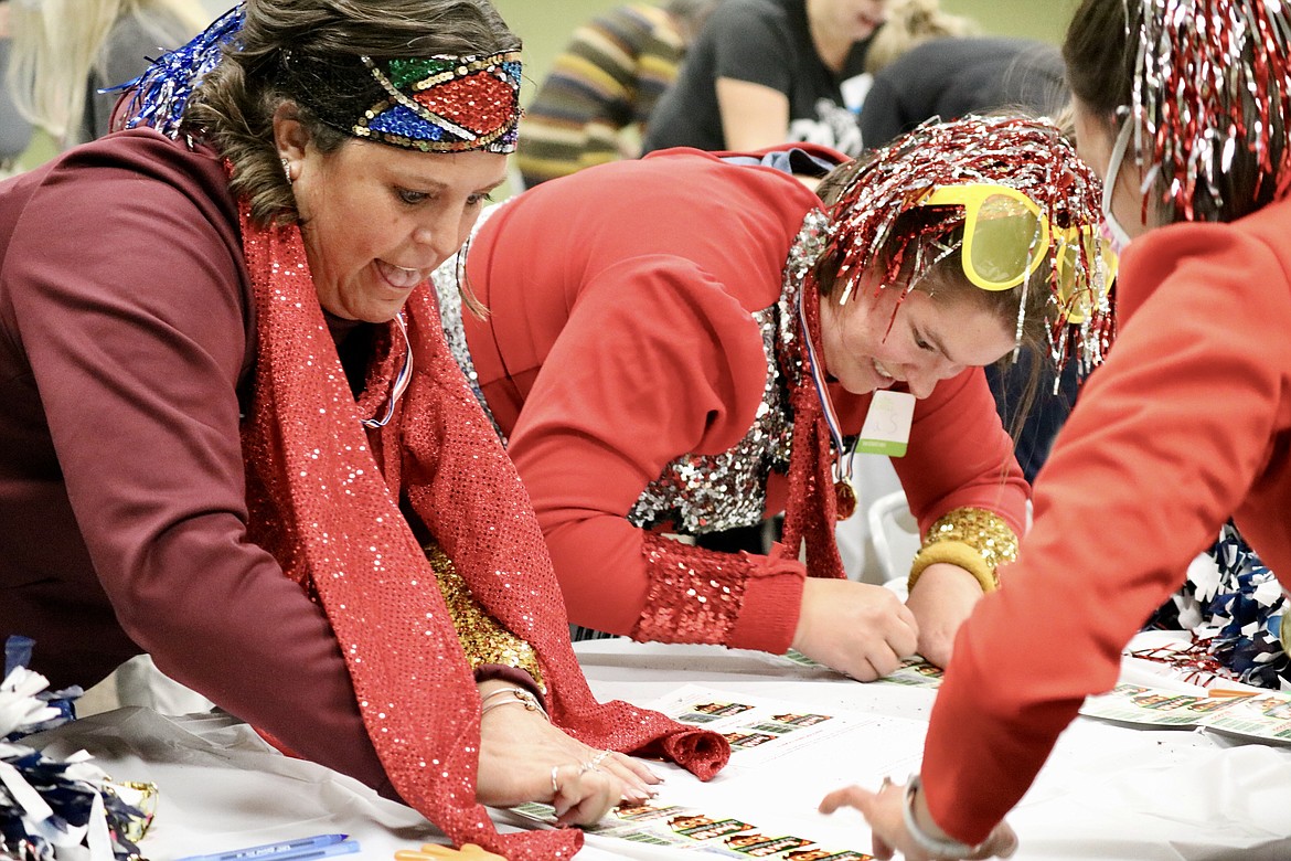 From left, Michele Torres and Julia Smulkowski, staff of Lakes Middle School, scratch their tickets at the public school fundraiser by the Idaho Lottery on Thursday evening at North Idaho College. HANNAH NEFF/Press