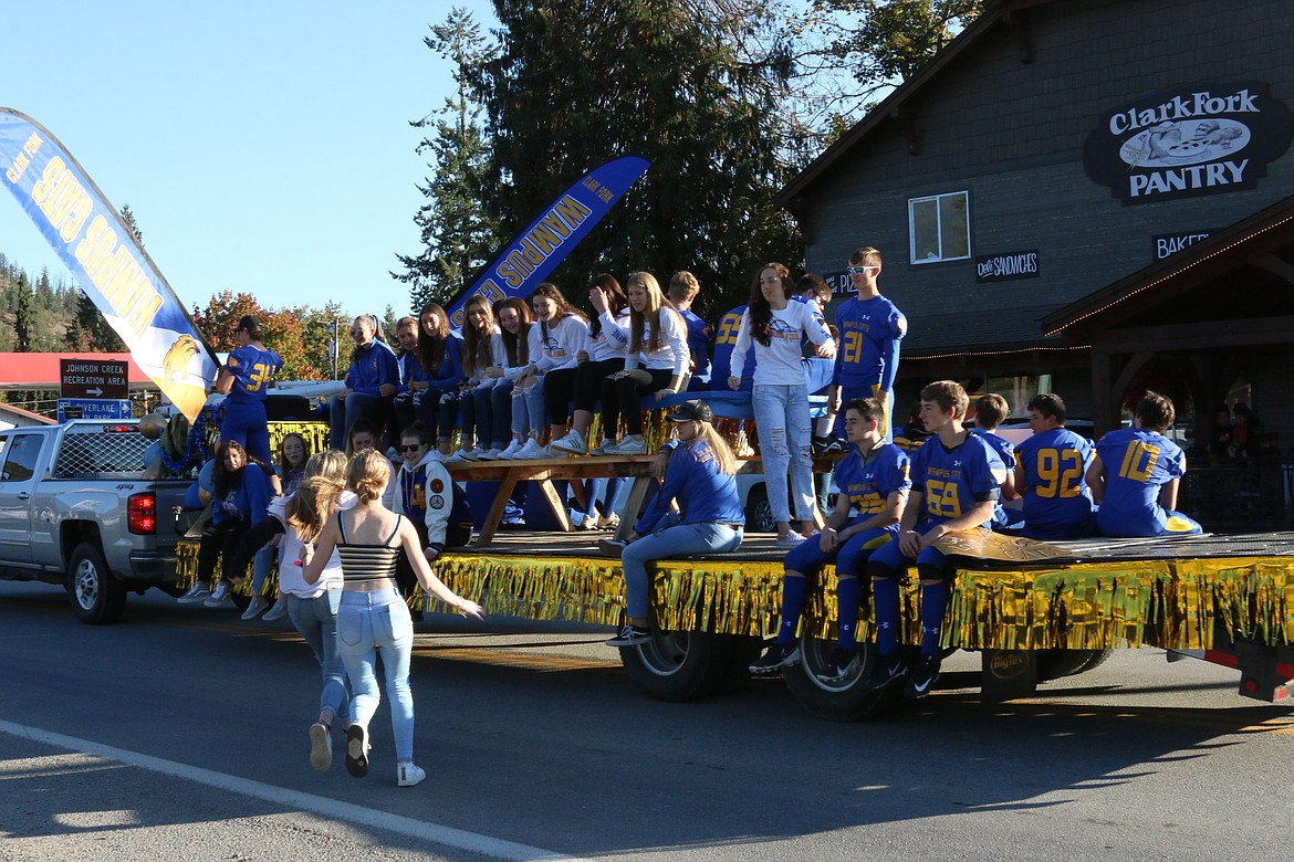 CFHS students ride on parade float. Other students catch a ride.