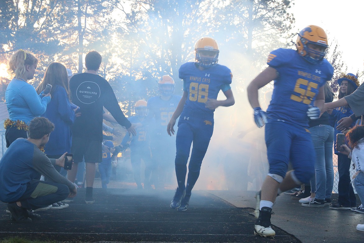 Wampus Cats football team rushing on field through student tunnel.