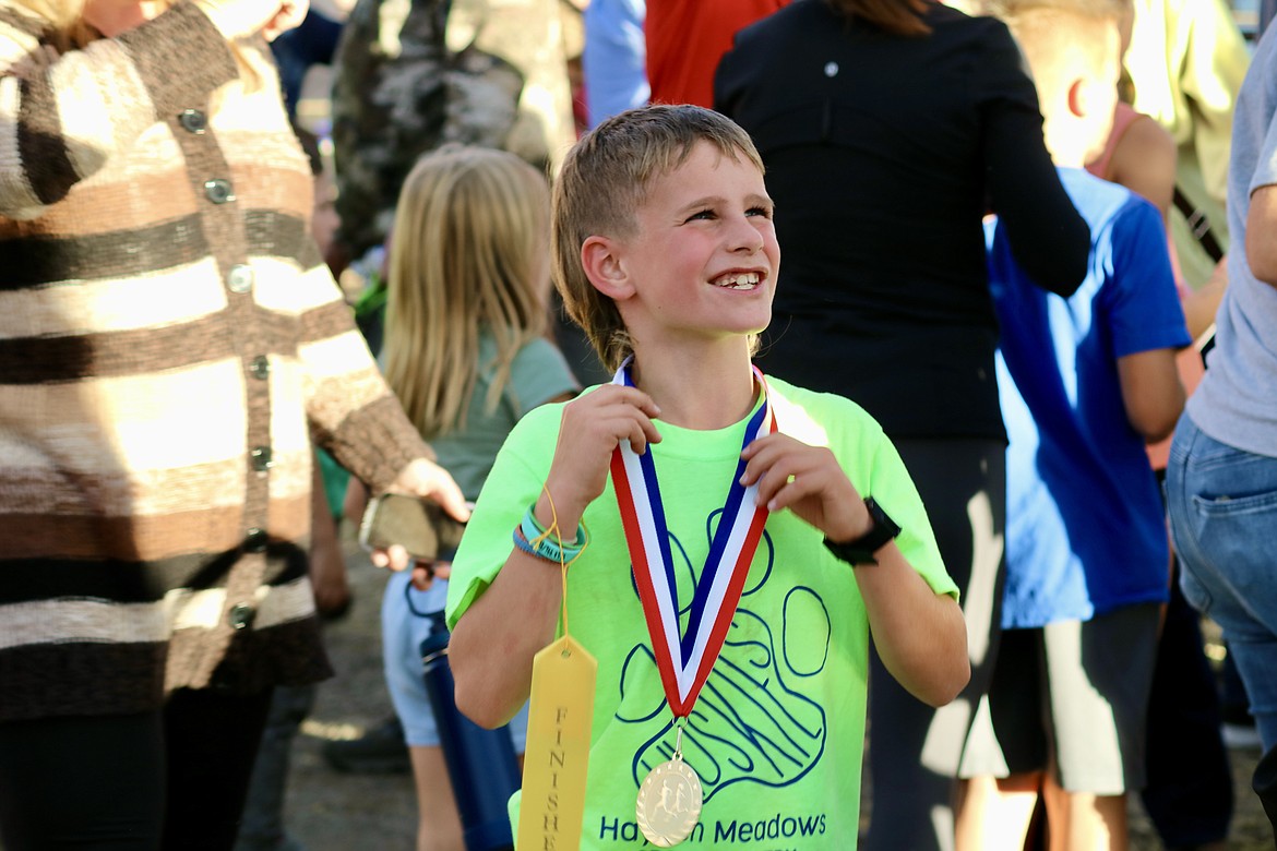 Wyatt Beasley, a third grader at Hayden Meadows Elementary School, smiles as he shows his dad his first place medal at the Coeur d'Alene School District cross-country race at the Kootenai County Fairgrounds on Thursday. HANNAH NEFF/Press