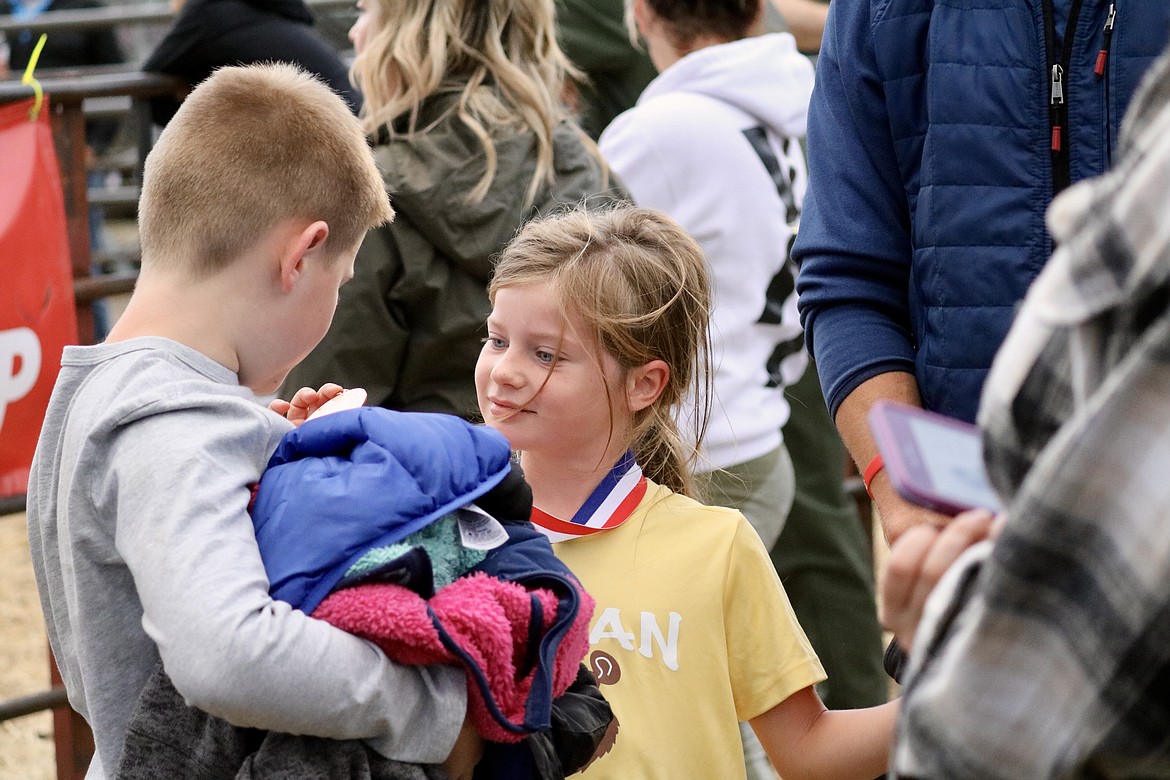 Harper Andersen, a second grader at Bryan Elementary School, beams as she shows brother Rhen her third place medal at the Coeur d'Alene School District cross-country race on Thursday evening at the Kootenai County Fairgrounds. HANNAH NEFF/Press