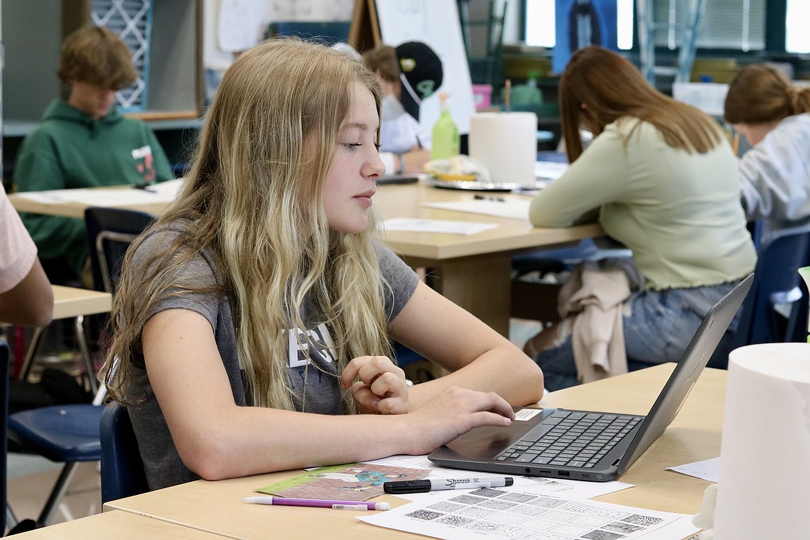 Taylor Winey works on an art project at Lake City High School. The newspaper clipping beside her is a project she worked on for an ethics lesson where students had to change the photo at least 50% to make it their own. HANNAH NEFF/Press