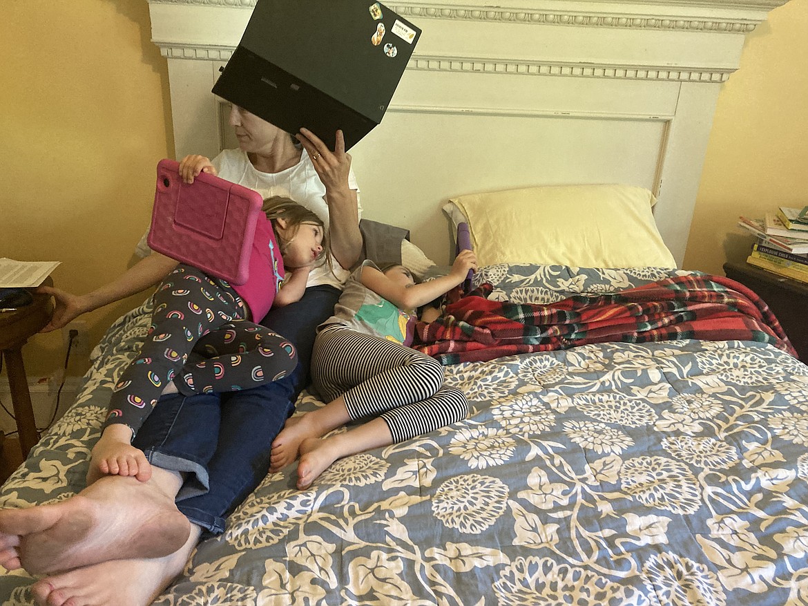 Beagan Wilcox Volz works on her computer as daughters Karen (left) and Anna watch videos while quarantining at home in Helena on Sept. 24.(MATT VOLZ / KHN)