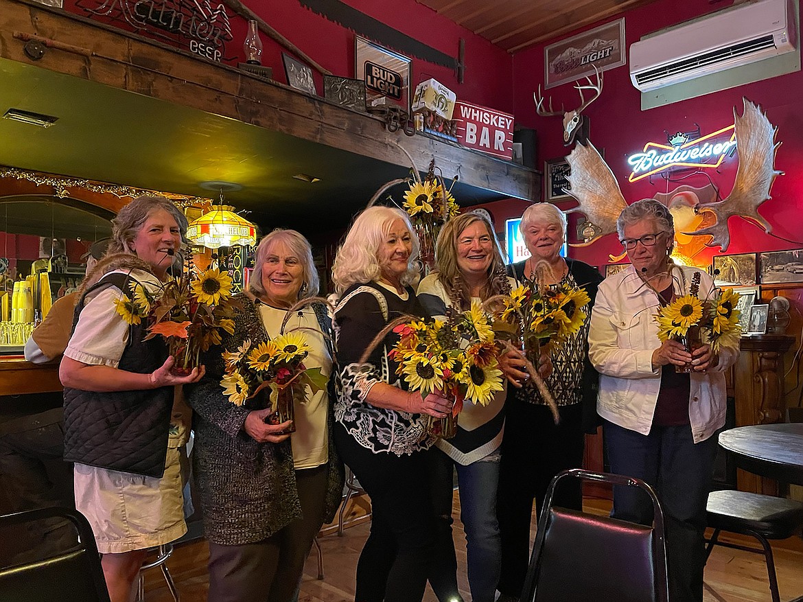 Mirror Lake Ladies Golf members hold their end-of-the-year dinner sunflower bouquets.