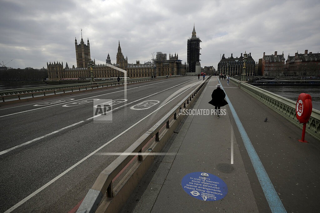 In this Tuesday, March 23, 2021 file photo, people pass over a quiet Westminster Bridge, backdropped by the scaffolded Houses of Parliament and the Elizabeth Tower, known as Big Ben, in London, during England's third coronavirus lockdown. The British government waited too long to impose a lockdown in the early days of the COVID-19 pandemic, missing a chance to contain the disease and leading to thousands of unnecessary deaths, lawmakers concluded Tuesday, Oct. 12, 2021 in a hard-hitting report. (AP Photo/Matt Dunham, File)