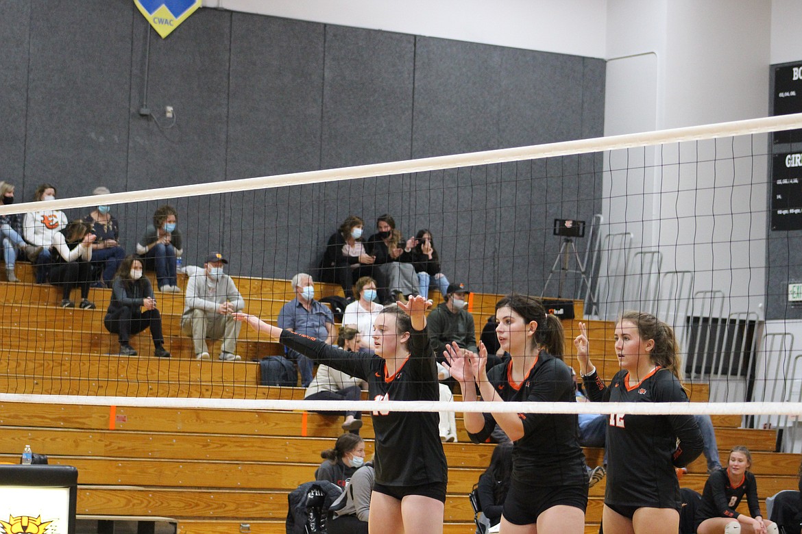 Three players for the Tigers prepare behind the net for a serve by East Valley.