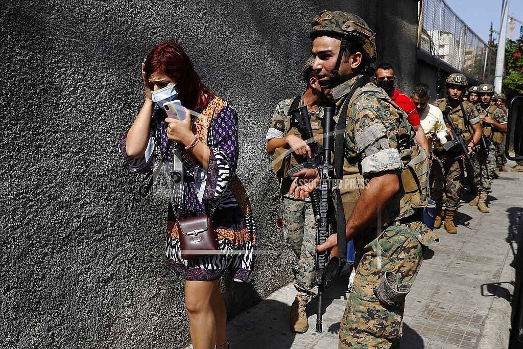 Lebanese army special forces soldiers protect teachers as they flee their school after deadly clashes erupted along a former 1975-90 civil war front-line between Muslim Shiite and Christian areas, at Ain el-Remaneh neighborhood, in Beirut, Lebanon, Thursday, Oct. 14, 2021. Armed clashes broke out in Beirut Thursday during the protest against the lead judge investigating last year's massive blast in the city's port, as tensions over the domestic probe boiled over. (AP Photo/Hussein Malla)