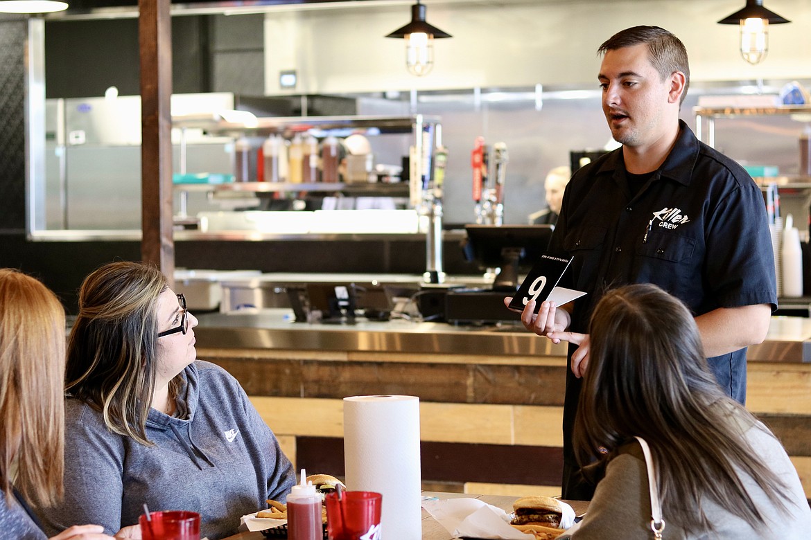 Mr. Corombes, assistant manager of the new Killer Burger location, who declined to give his first name, serves a group during Friday's soft opening. HANNAH NEFF/Press