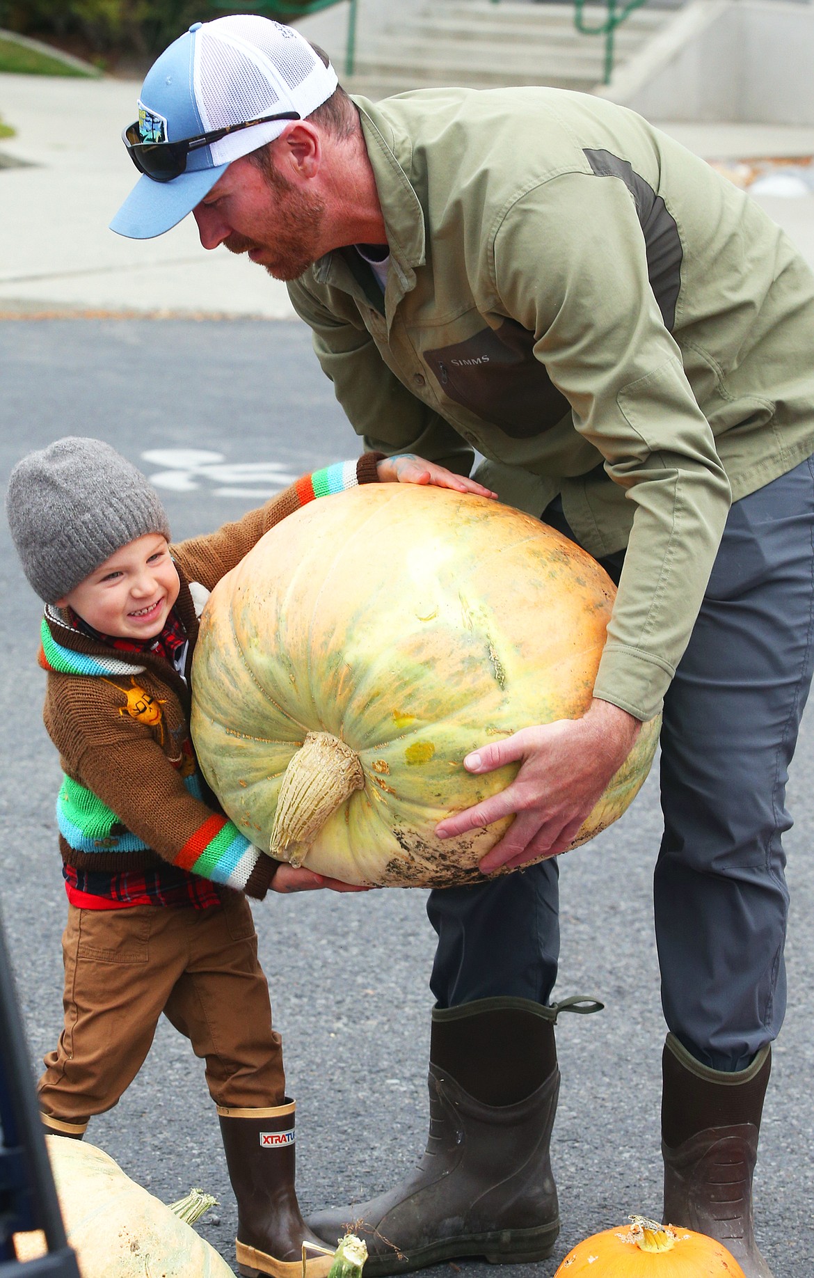 Dustin Stetson gives a hand to son Jack at the pumpkin giveaway outside City Hall on Friday.