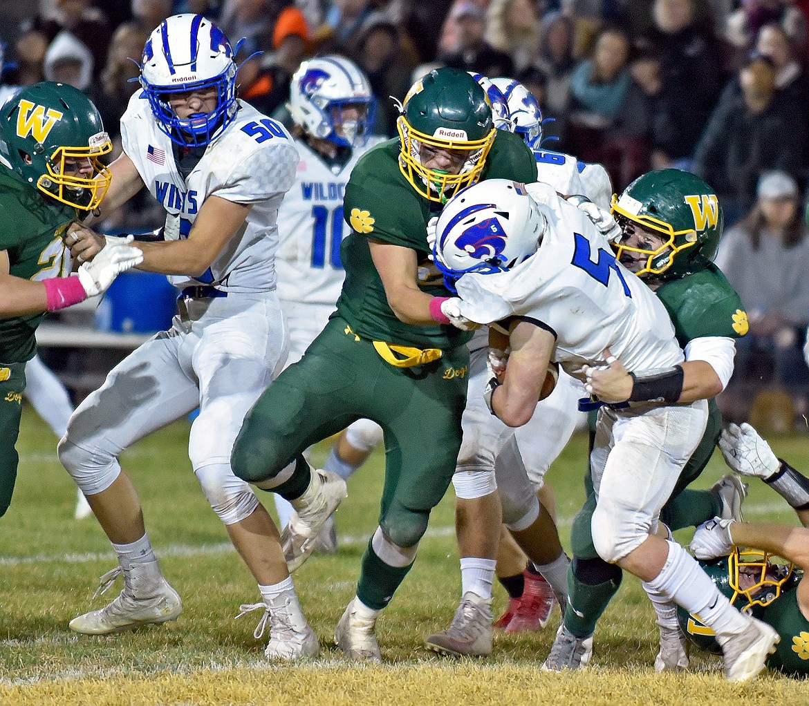 Whitefish's Ty Schwaiger (left) and Tanner Harmon (right) combine to tackle Wildcat Isaiah Roth during a game against Columbia Falls on Friday in Whitefish. (Whitney England/Whitefish Pilot)