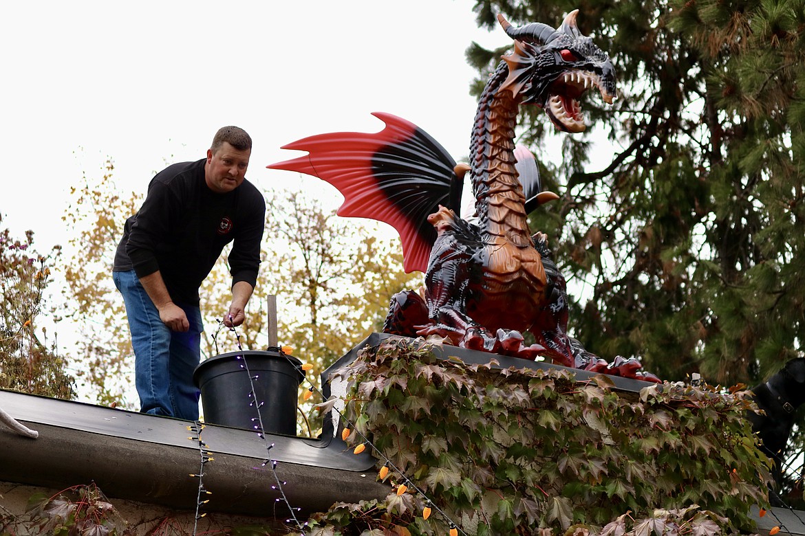 Jake Bieker strings lights from his roof out toward the street on Friday to create a spider web effect for Halloween at his home on Government Way. HANNAH NEFF/Press