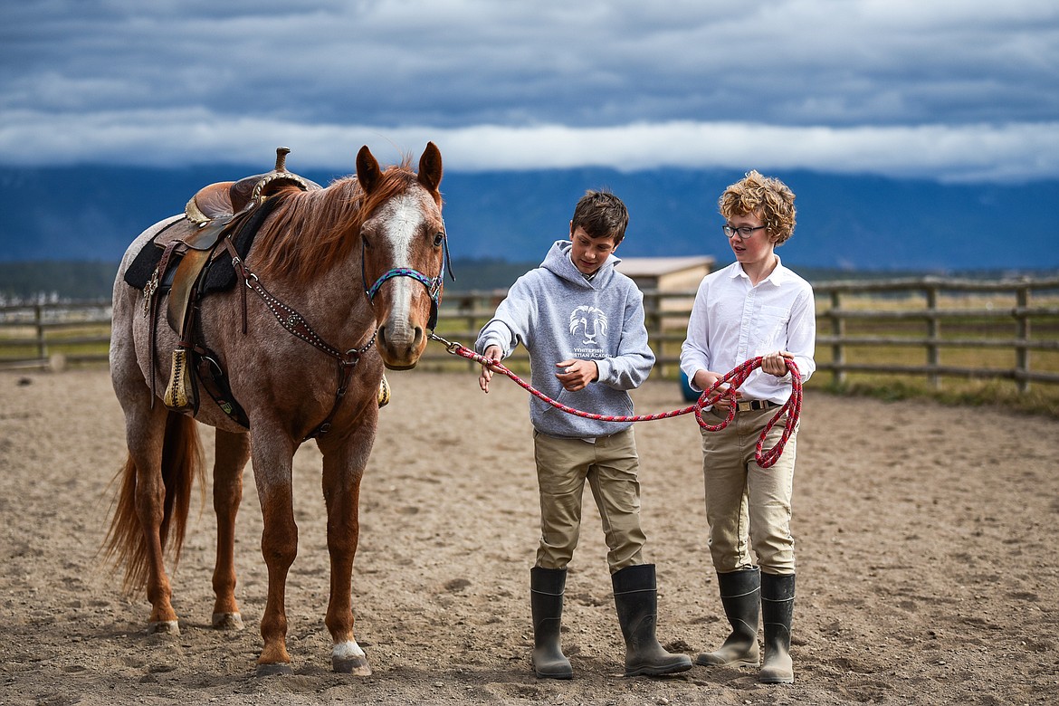 Austin Alton, left, hands the lead to Jack Flink, both seventh-graders at Whitefish Christian Academy, during a class on horsemanship at Lost Creek Ranch on Friday, Oct. 15. (Casey Kreider/Daily Inter Lake)