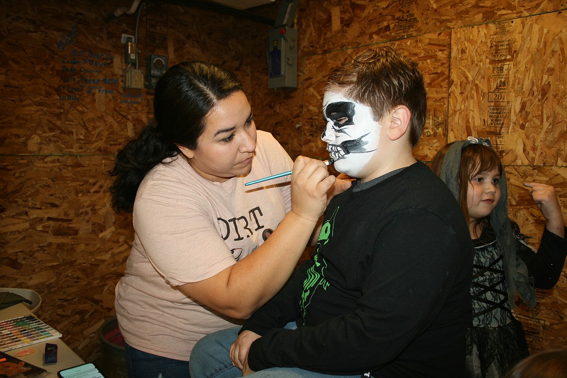 Stephanie Carl (left) paints a scary face on Travis McIndoe for the Othello Straw Maze Friday.
