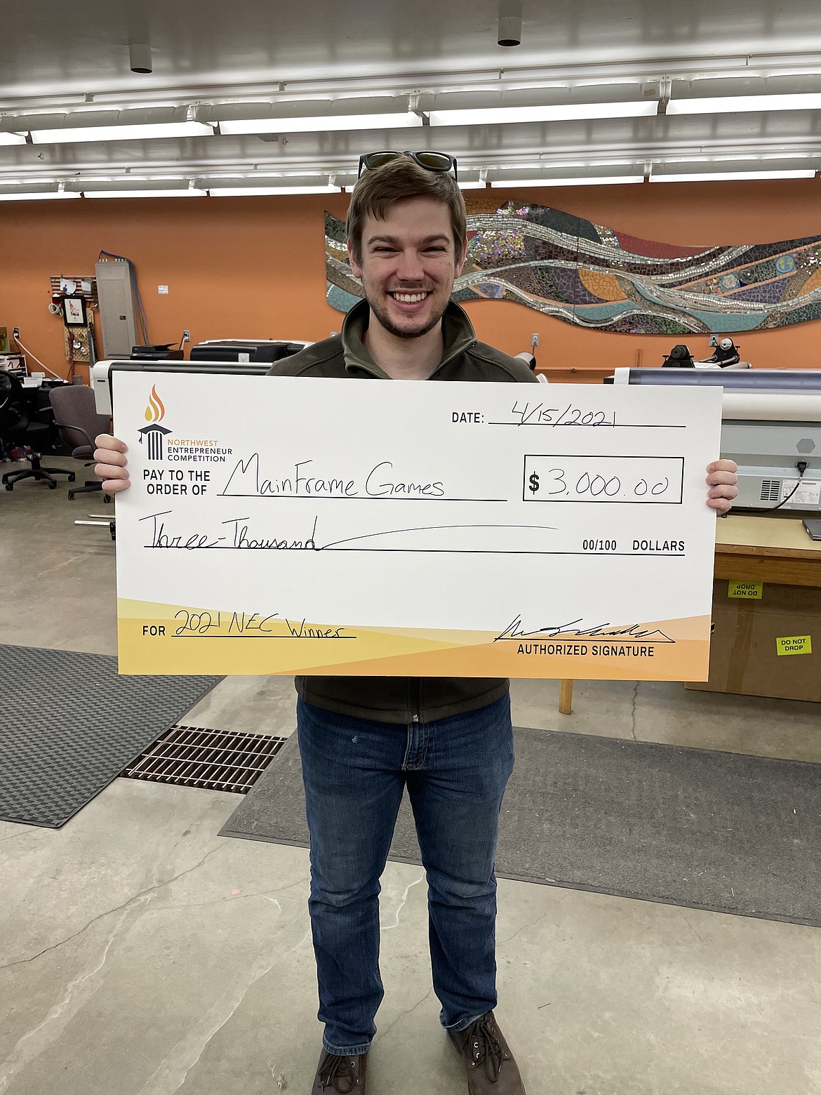 Issac Cunnington holds his "big check" from the Northwest Entrepreneurial Competition. Cunnington and friend Mikel Buffloe formed Mainframe Games and took second place in the open category early this year.
