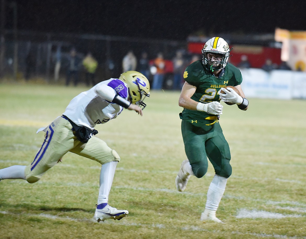 Bulldog Ty Schwaiger carries the ball down the field avoiding a Polson defender Friday night at the Dawg Pound. (Heidi Desch/Whitefish Pilot)
