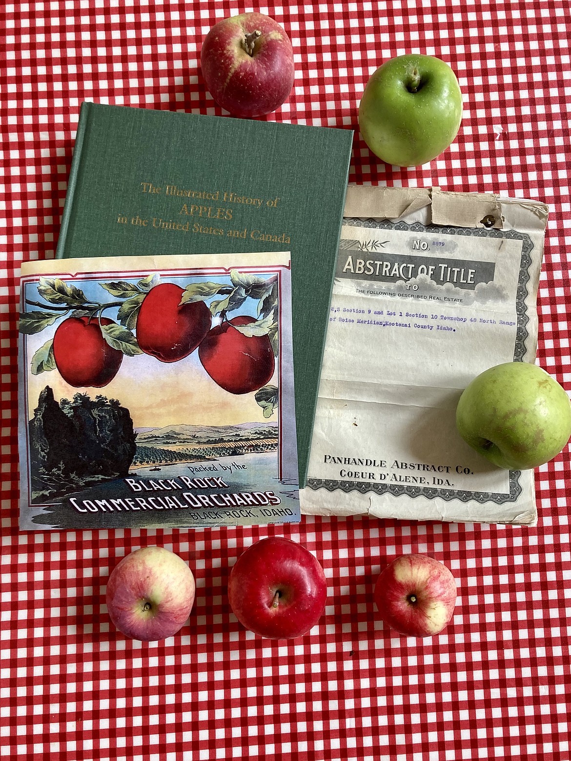 Pictured items include a label for Black Rock Commercial Orchards found at a museum in Yakima by the Glover family's relatives, the original title for the property, an apple research book and fruit from the 120-plus year old apple trees. HANNAH NEFF/Press