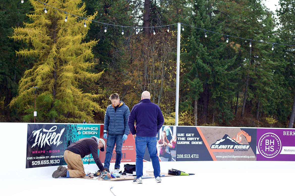 From left, Herb Thom, co-owner Jerome Murray, and Kent Layden work to install lights under the ice at the new ice skating rink, Coeur d'Alene on Ice, on Monday. The rink opens at 10 a.m. Saturday and will be open daily until Jan. 2, weather permitting. HANNAH NEFF/Press