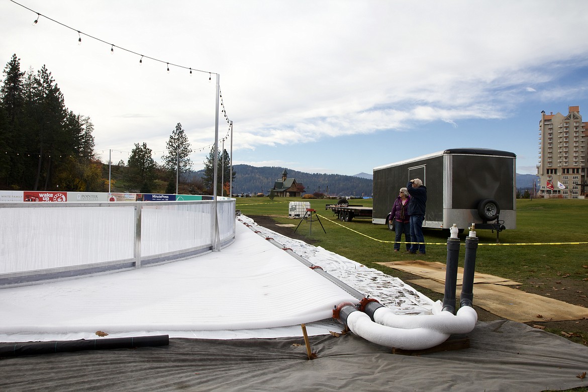 Coeur d'Alene residents including Russell and Doreen Kruger, volunteers at the Coeur d’Alene Chamber Visitors Center, stopped by McEuen Park Monday to check  out the progress on the 80 by 120 foot ice skating rink, Coeur d'Alene on Ice, opening Saturday. HANNAH NEFF/Press