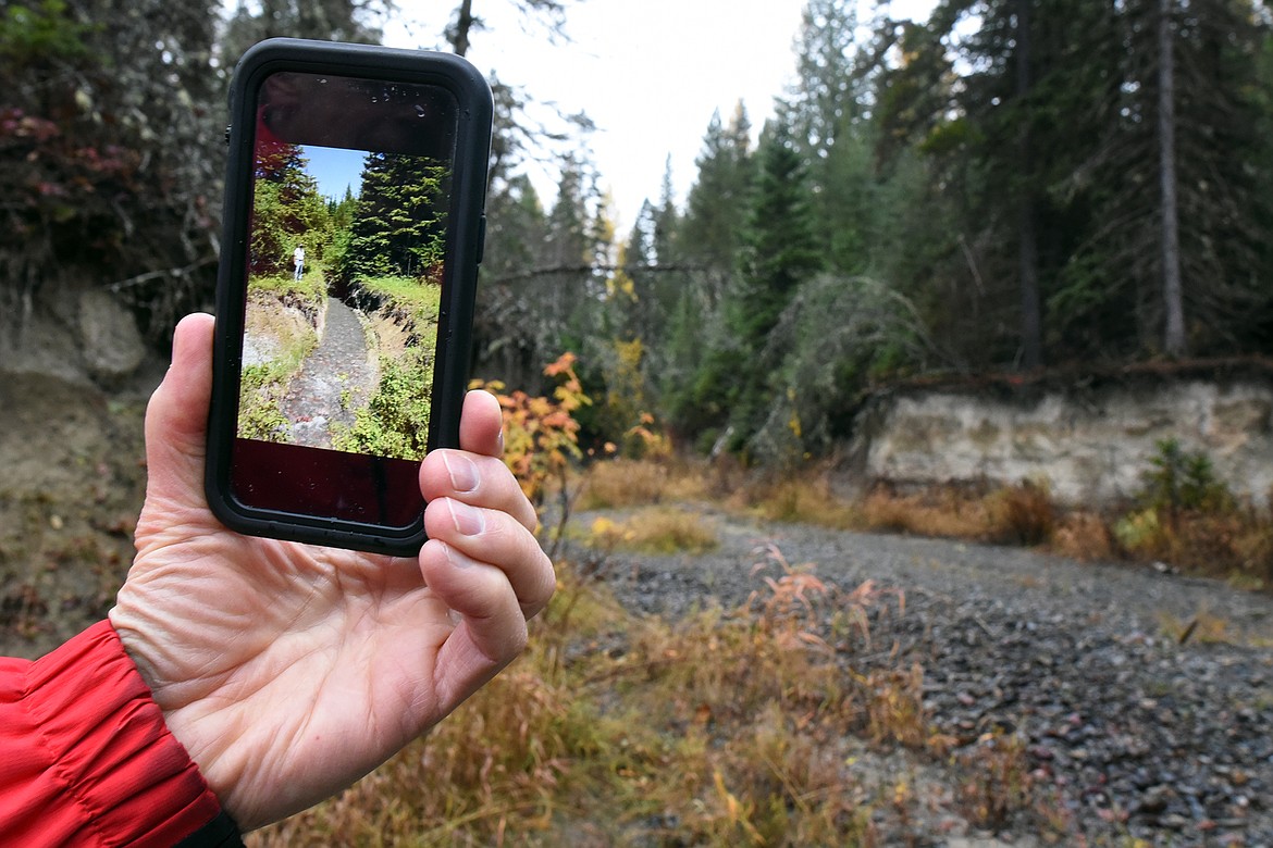 Landowner Don Garner stands Monday, October 25 in the same spot shown in the picture on his phone of Krause Creek after it flooded in June 2005. A new project taken on by the Flathead Conservation District hopes to help return the creek to its former state. (Jeremy Weber/Daily Inter Lake)