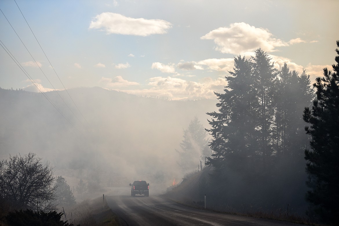 A truck passes a grass fire burning on a hillside along West Valley Drive on Wednesday, Oct. 27. A fire tanker from Smith Valley Fire Department was driving back and forth on West Valley Drive monitoring the fire. (Casey Kreider/Daily Inter Lake)