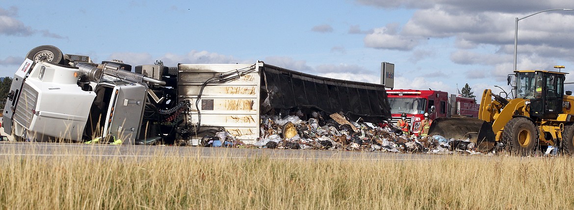 A front-end loader pushes an overturned trailer of trash from U.S. 95 on Wednesday.