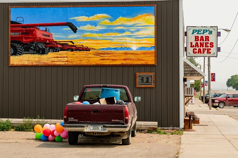 Outside of Pep’s Bar, Cafe and Lanes, a mural captures the spirit of Big Sandy: Seven red combines line up in a wheat field at sunrise, ready to harvest a local farmer’s crops after he was diagnosed with cancer. (Jason Thompson/MTFP)