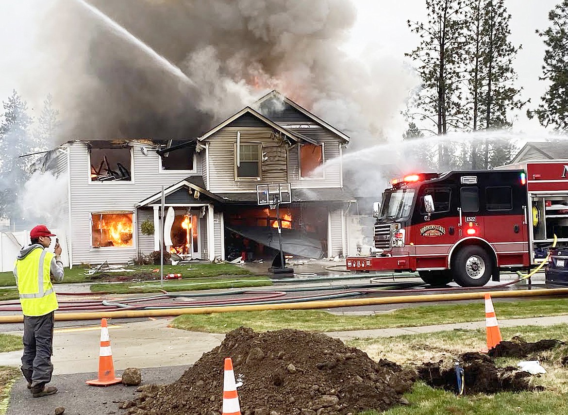 Photo by Tyler Drechsel
Firefighters spray water on a Rathdrum home burning Thursday following an explosion believed to be caused by a natural gas leak earlier in the day.