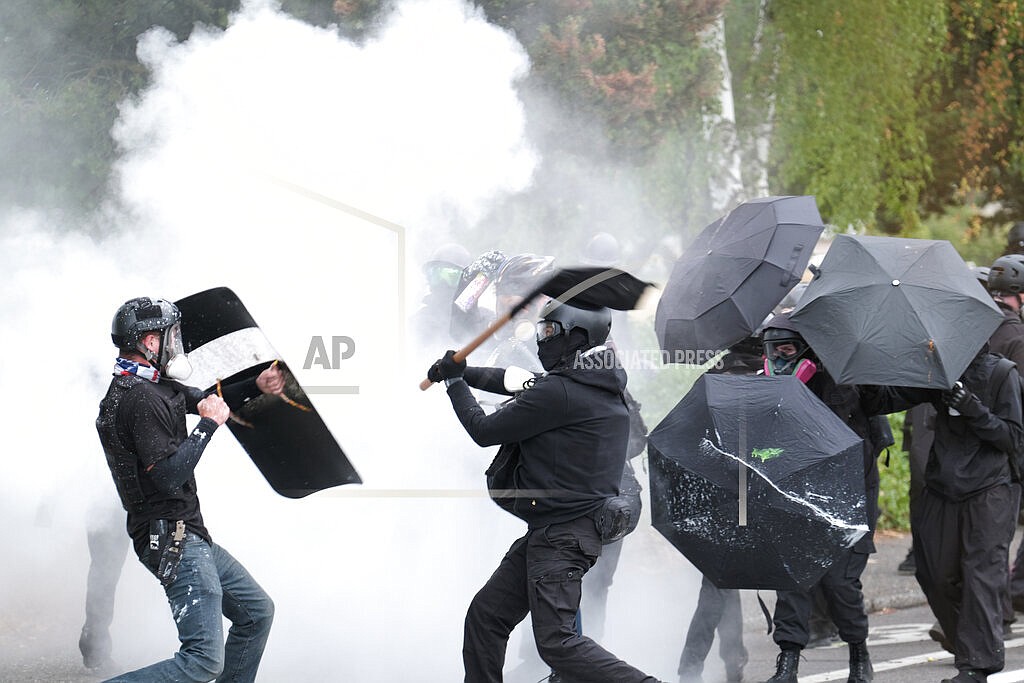 An anti-fascist protester swings a baton as members of the far-right Proud Boys advance during clashes between the politically opposed groups on Sunday, Aug. 22, 2021, in Portland, Ore. The city's leaders were told this week that Portland's "badly damaged" reputation – marked by months of destructive protests – continues to hurt the standing of Oregon's largest city in the eyes of potential visitors. (AP Photo/Alex Milan Tracy, File)