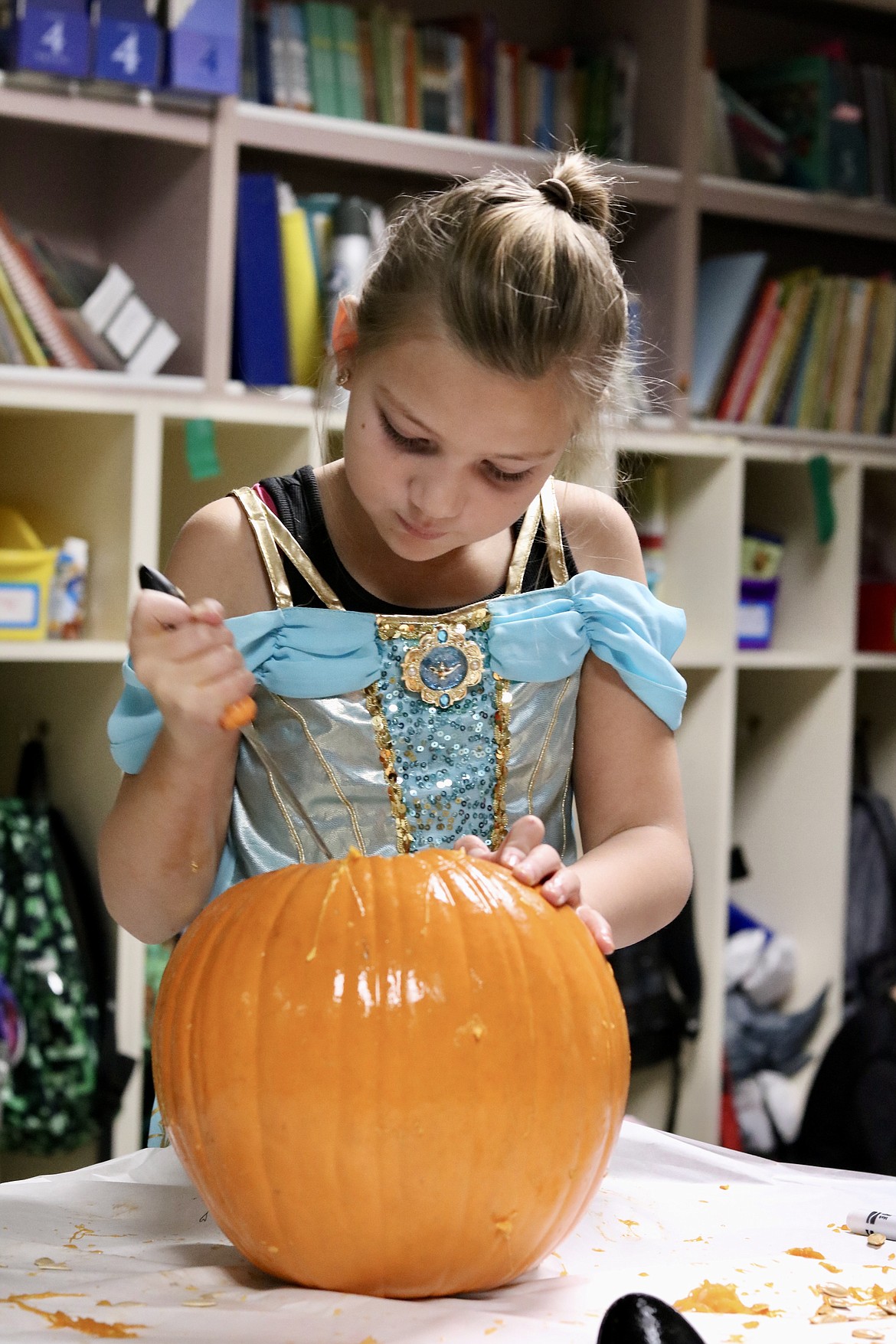 Dressed in a Princess Jasmine costume, fourth grader Bella Dirks guts a pumpkin at Fernan STEM Academy in Coeur d'Alene on Friday. HANNAH NEFF/Press