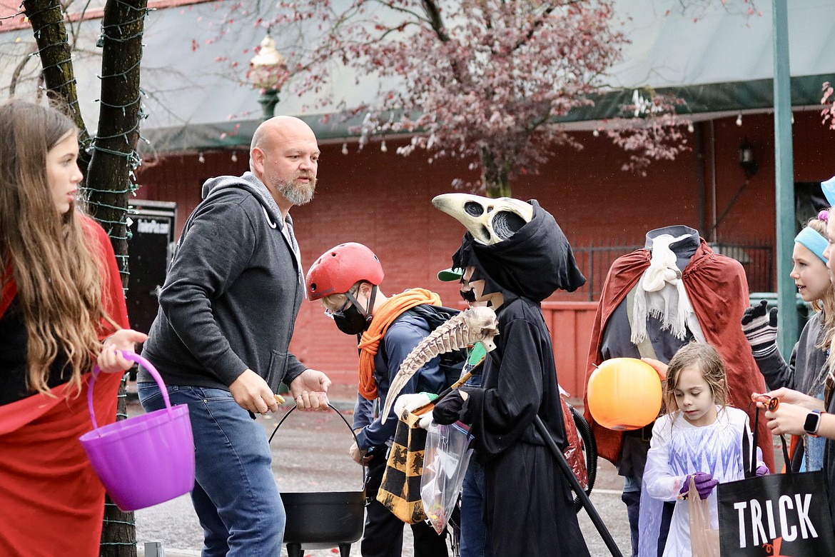 Ben Drake, co-owner of The Crown & Thistle pub, stands at the corner of Fourth Street and Sherman Avenue to hand out candy to the 315 trick or treaters from Sorensen Magnet School of the Arts and Humanities, an elementary school in Coeur d'Alene, on Friday. HANNAH NEFF/Press