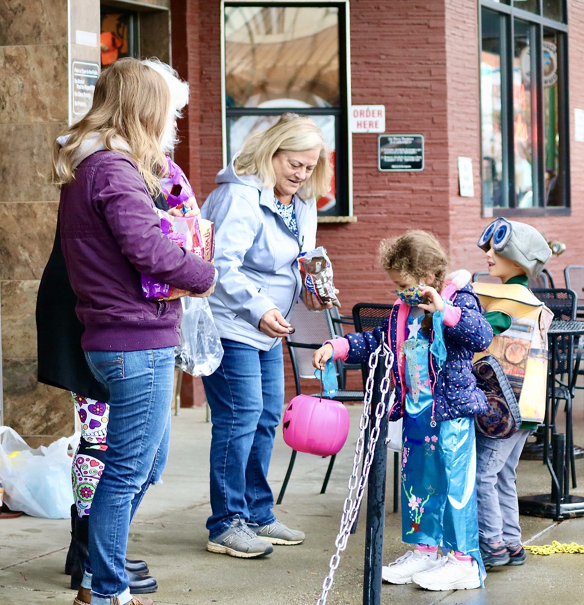 Kathy South, a member of the Coeur d'Alene Fraternal Order of Eagles, hands out candy to a trick or treater from Sorensen Magnet School of the Arts and Humanities during the school's annual costume parade down Sherman Avenue on Friday. HANNAH NEFF/Press