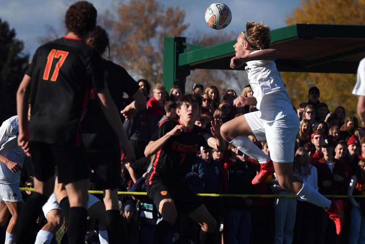 Glacier’s Caleb Heil jumps high above Hellgate’s Dylan Adams to head the ball during action at the Class AA state soccer championship in Missoula Saturday. (Jeremy Weber/Daily Inter Lake)