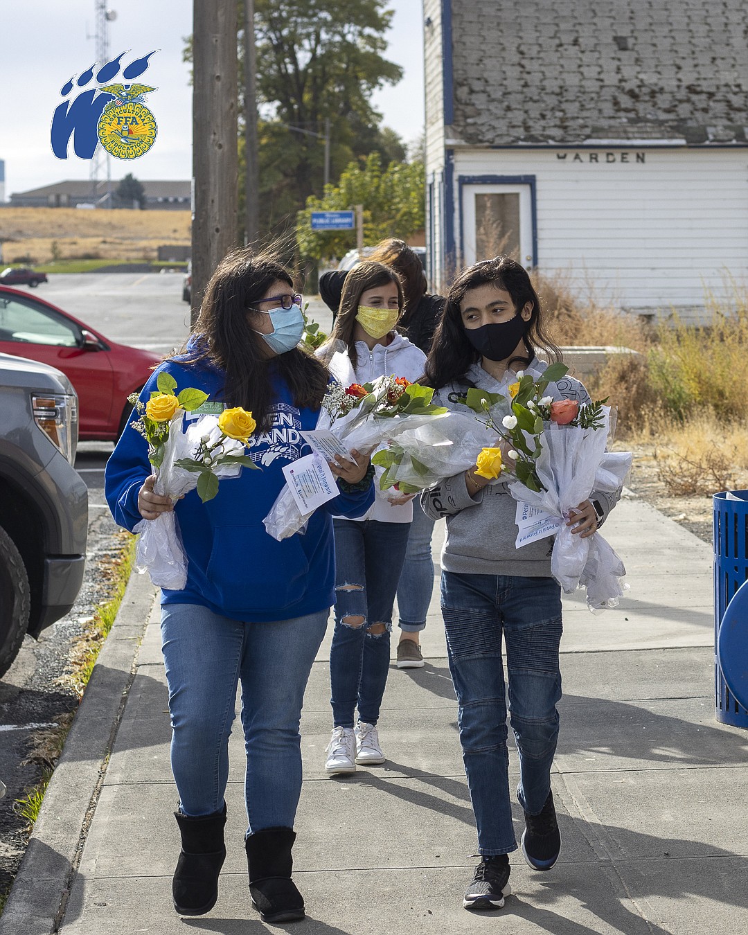 From left to right, Ariana Arceta, Daisy Leavitt (in back) and Jesus “Sky” Lemus Estrada carry flowers down the streets of Warden as they find community members to give them to on Oct. 20.