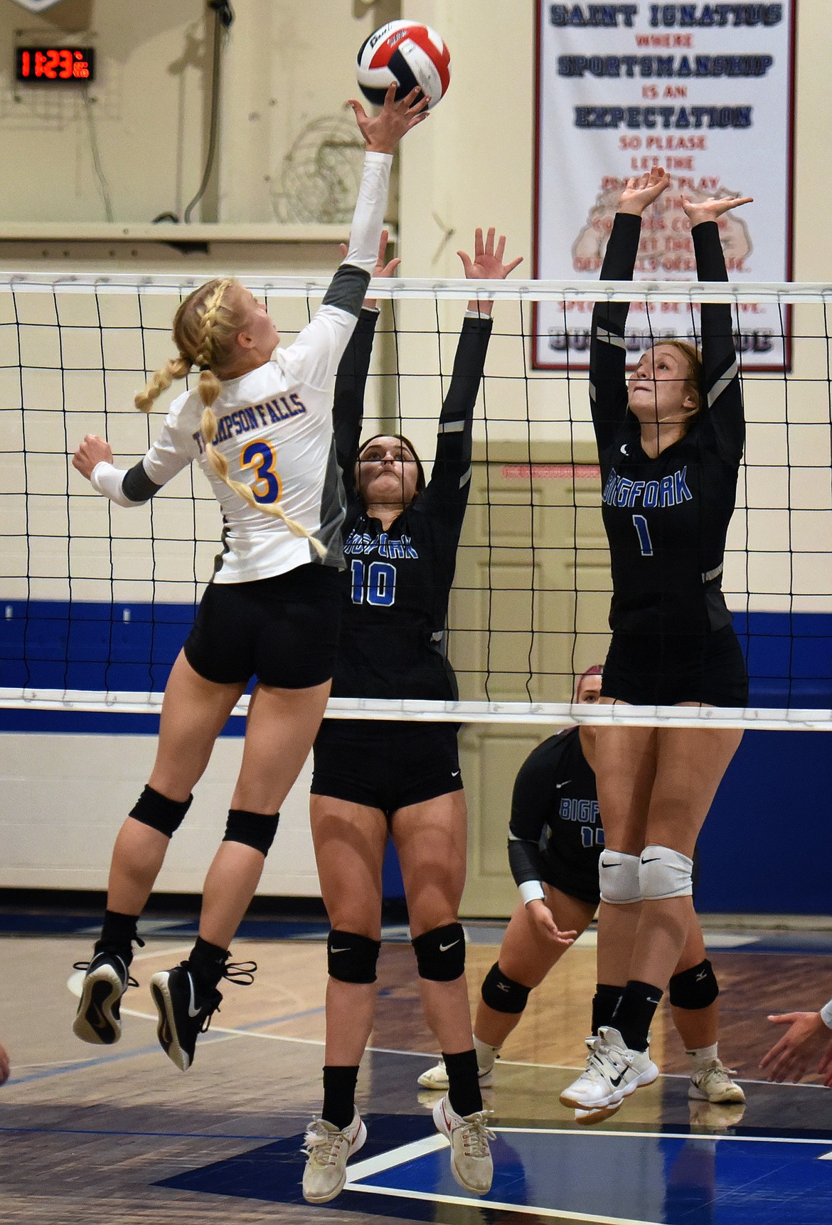 Scarlette Schwindt (3) of Thompson Falls goes high above the net to hit the ball past Bigfork defenders Arianna Saari (10) and Inga Turner (1) during action at the 7B District Volleyball Tournament in St. Ignatius Saturday.