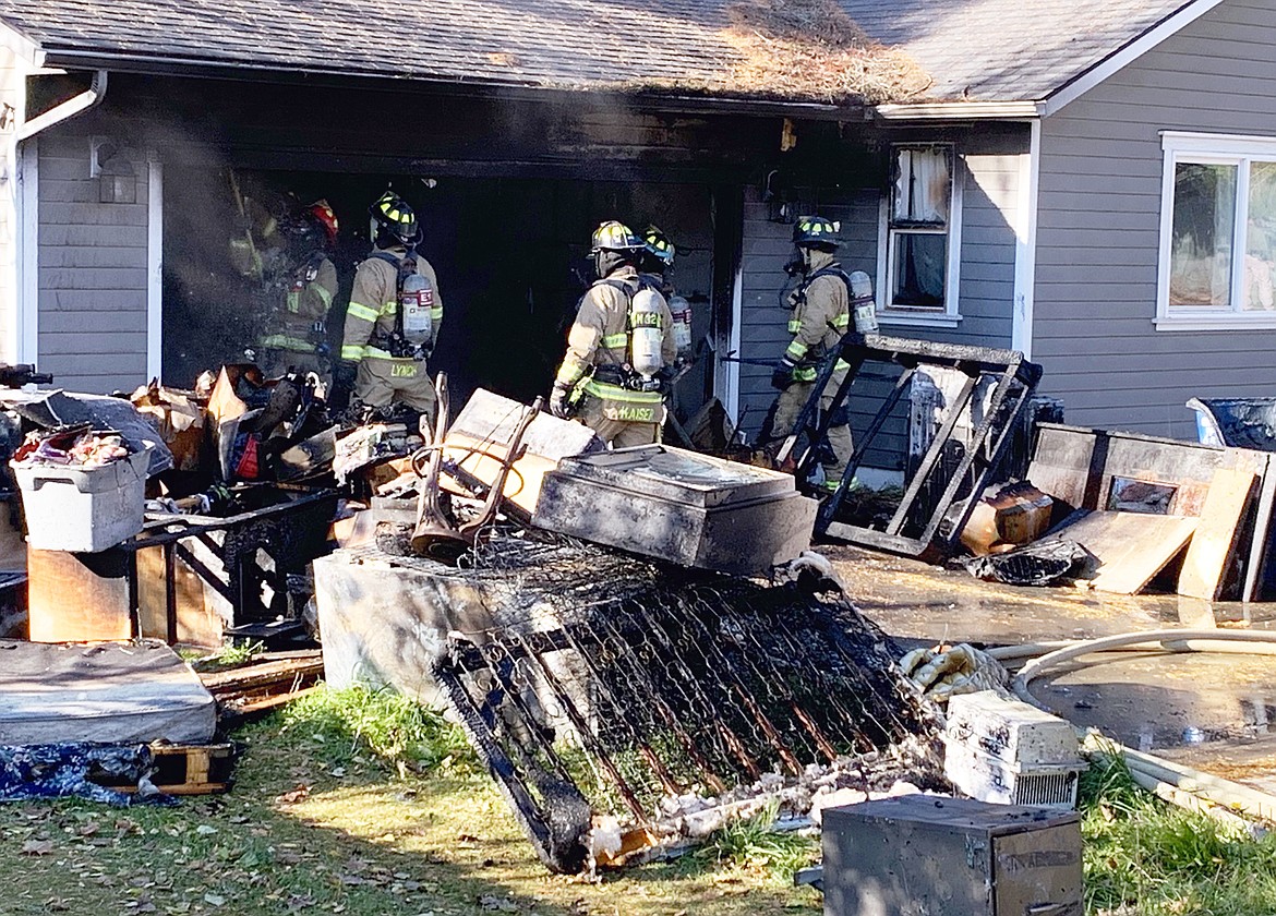 Northern Lakes Fire Protection District and Coeur d'Alene firefighters remove contents from the Hayden garage that suffered extensive damage in a fire Monday.