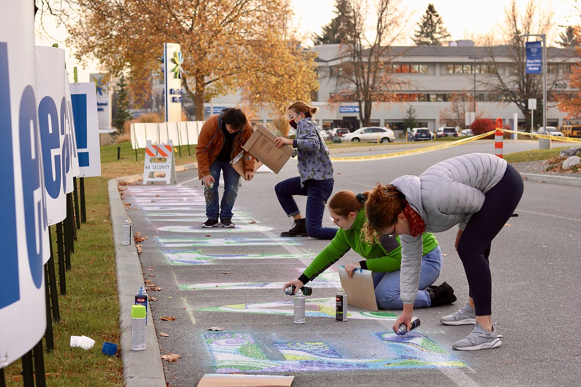 From left, North Idaho College students Damian Maxwell, Sadie Bouwens, Grace Michelsen and Annie Vladovska spray paint graffiti on the pavement on Kootenai Health Way, on the east side of the hospital in a thank you message to health care workers through a collaboration between Kootenai Heath and the Associated Students of North Idaho College. HANNAH NEFF/Press