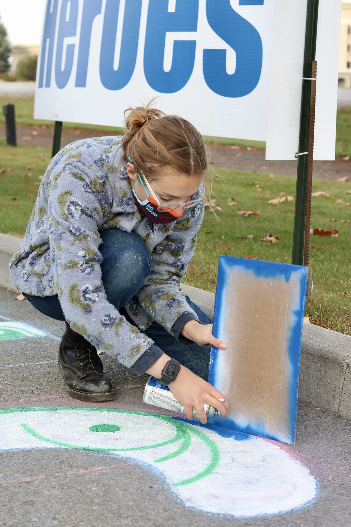 North Idaho College student Sadie Bouwens spray paints a thank you message to health care workers on the pavement of Kootenai Health Way on the east side of the Kootenai Health, adjacent to U.S. 95, on Monday. HANNAH NEFF/Press