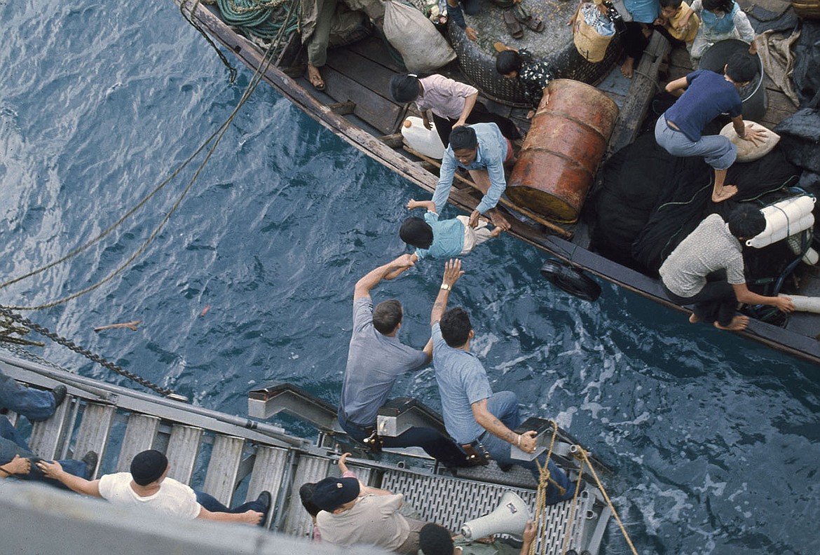 Crewmen of the USS Durham amphibious cargo ship take Vietnamese refugees from a small craft in 1975, with 140,000 Vietnamese and Cambodians admitted within months after the end of the Vietnam War.