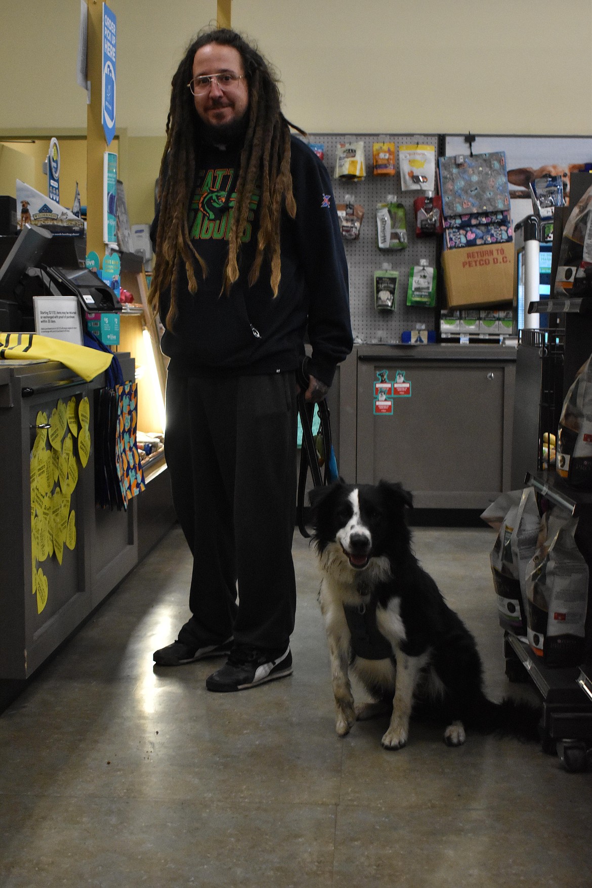 Tyler Scott poses with his dog, Wilson, while checking out at Petco in Moses Lake on Wednesday. Scott bought Wilson a yellow raincoat on the rainy, gloomy afternoon. Scott said Wilson was named after Seahawks quarterback Russell Wilson. Wilson, the dog, has a brother called Russell, named in the same fashion, according to Scott.